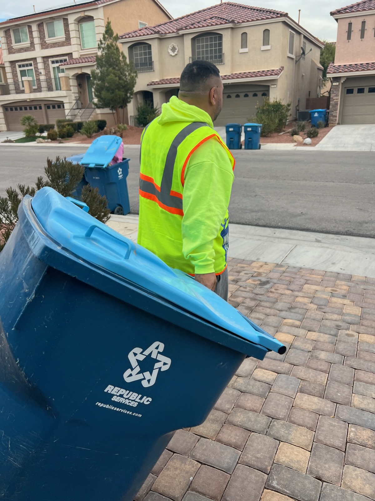 Win City Bins crew member rolling a residential trash bin to the curb in a Las Vegas neighborhood